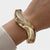 Bracelet manchette vague ton doré porté au poignet
