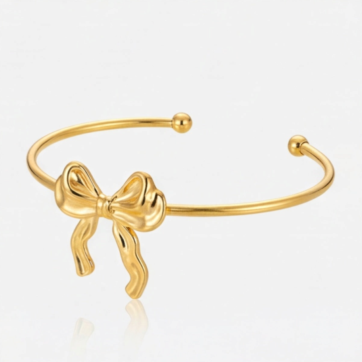 Brazalete cuff abierto con lazo en tono dorado inclinado con puntas redondeadas