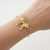 Slanke goudkleurige cuff-armband met strik om de pols gedragen