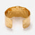 Wide gold-tone open cuff bracelet viewed from the back