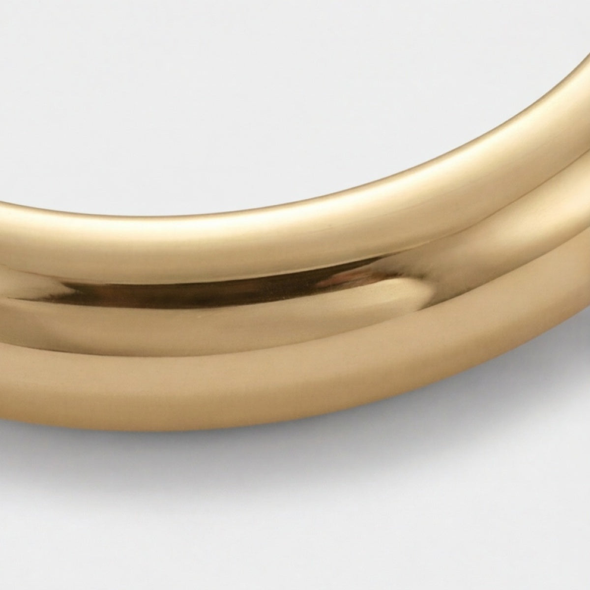 Nahaufnahme der Kurve eines glatten goldfarbenen Armreifs
