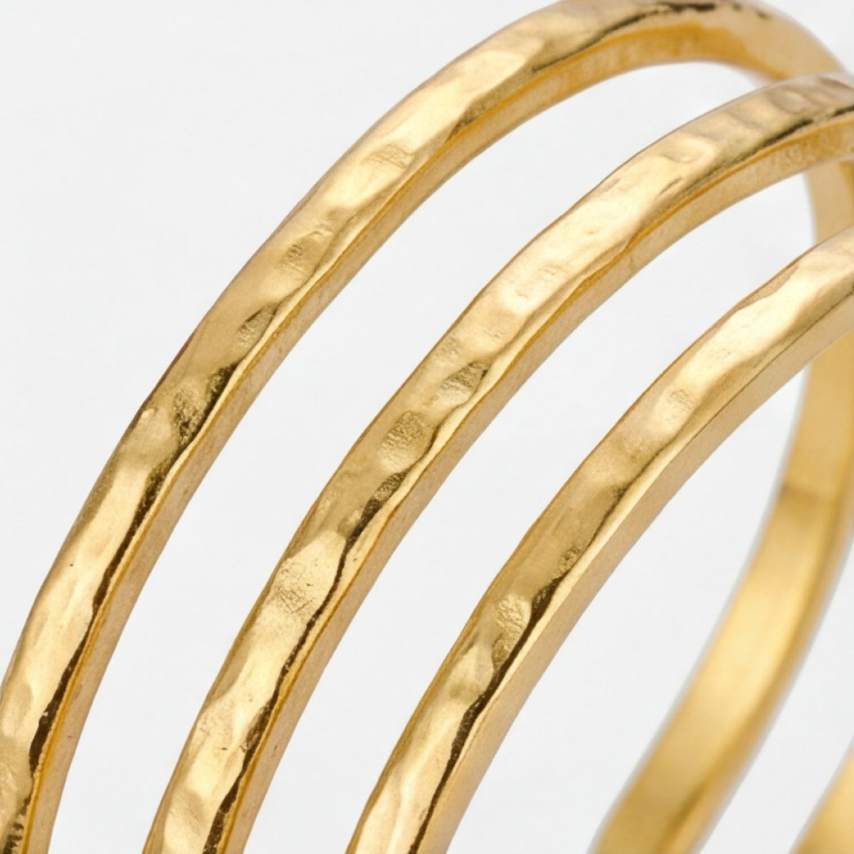 Nahaufnahme der getrennten geschwungenen Bänder des goldfarbenen Armreifs
